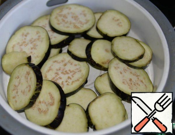 Wash the eggplants, cut into slices and simmer until half cooked. To do this, I put an insert from a slow cooker on top of a pan with potatoes for steaming, you can put a colander. Cook the eggplant for 10 minutes.