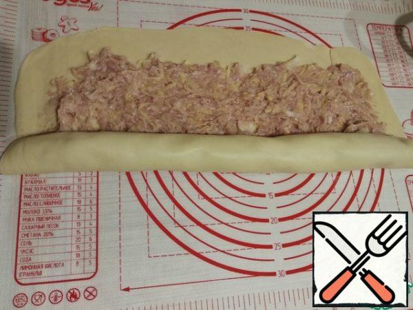 Divide the dough into two parts and roll it out in layers, lay out the resulting minced meat and wrap it in a roll.