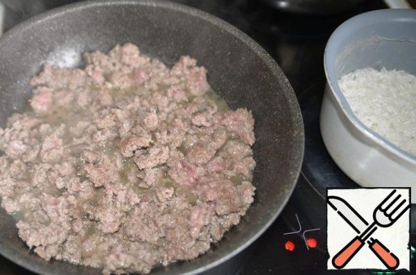 Wash the rice, pour water to cover the rice, bring to a boil and cook over medium heat until half cooked.
At the same time, pour oil into a hot pan, put the minced meat and fry until Golden. I have ground Turkey.
