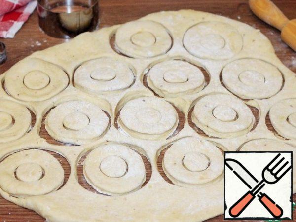 On the table top dusted with flour, roll out the dough into a layer 0.7 cm thick and cut out round buns.
Forming buns (tenderloin) to your taste.