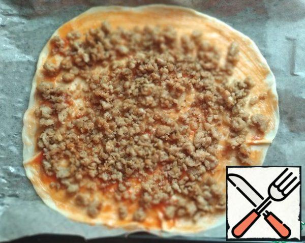 Roll out each part of the dough into a circle. Cover the baking sheet with baking paper and grease with vegetable oil. Transfer the first round of dough to a baking sheet. Grease with ketchup (1.5 tbsp), distribute half of the minced meat.