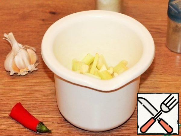 Prepare the sauce. In the bowl of a blender, put pieces of chopped celery, a little hot pepper and a clove of garlic. Add 50 ml of boiled water, mix and grind with a blender until smooth.