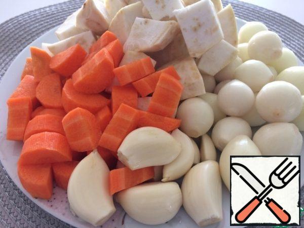 Peel the garlic and onion. You can use a regular onion, then you need to cut it large. We take a whole head of garlic, peel it from the husk, and use the whole cloves. Peel the carrot, cut it into the size of garlic cloves. Celery root choose the size of a tennis ball, clean it and cut into cubes.