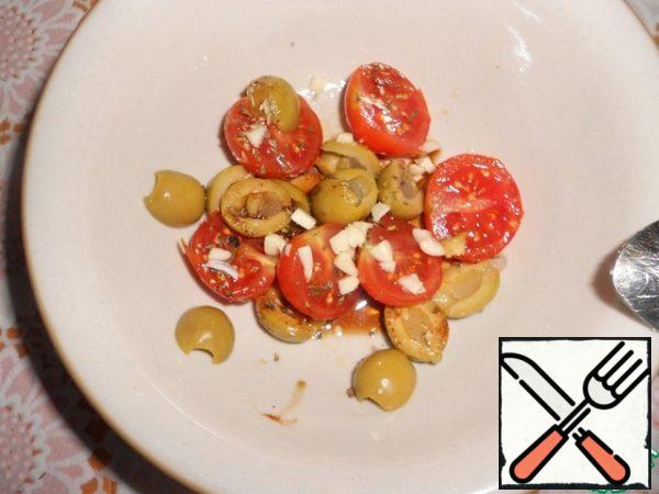 Add olive oil and soy sauce to the tomatoes and olives. Sprinkle with Basil, oregano and pepper and mix well. Peel the garlic, chop it finely and add it to the salad.