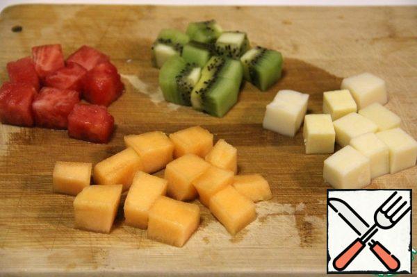 Cut the watermelon, kiwi, melon and cheese into cubes of the same size.