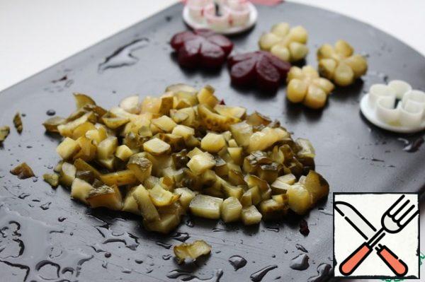 Cut the pickled cucumber into small cubes. If desired, you can make flowers from beets and cucumbers for decoration.