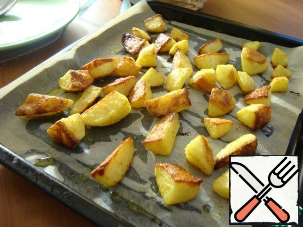 Peel the potatoes, wash and dry. Cut 1/8 of each potato. Place in a bowl. Pour in the butter, salt, and sprinkle with breadcrumbs and curry. Shake the dishes well so that each piece falls off, covering with a lid. Cover the baking sheet with baking paper and put the potatoes one by one on it.