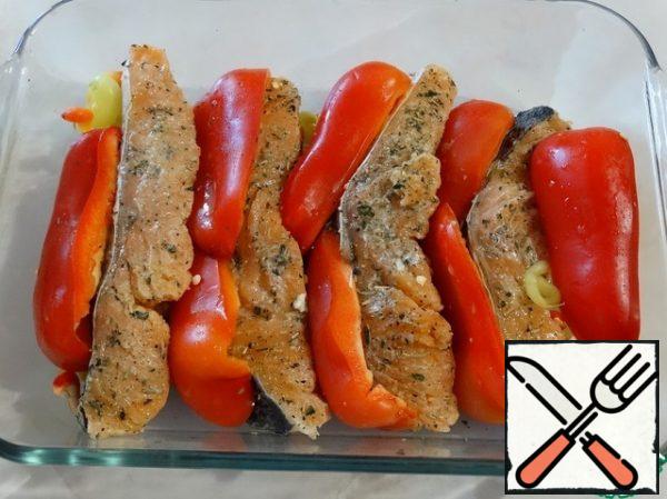 The form is greased with olive oil, put the fish, pour the remaining sauce. Put quarters of sweet pepper between the fish.