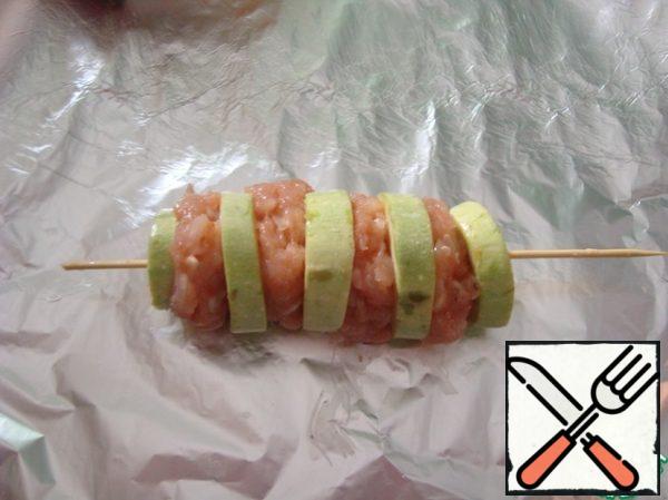 Take the foil, wooden skewers. We put the zucchini and minced meat alternately, first forming it into a ball with raw hands. Here you can sprinkle everything with grated cheese. I didn't put it on.