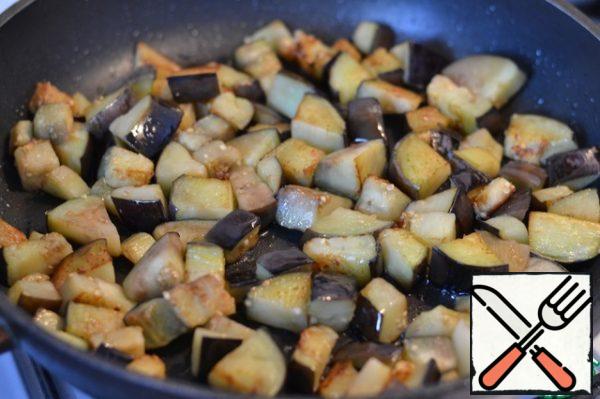 Cut the onion into half rings. Garlic in pieces.
Add to the eggplant and fry for 2 minutes.