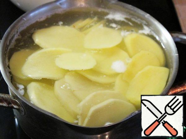 Cut the potatoes into thin slices. Boil in salted water until half cooked. Cut the onion into half rings.