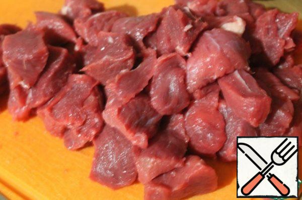 In a cauldron, heat the vegetable oil. Chop the meat into walnut-sized pieces.