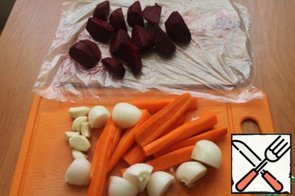 Wash the carrots and beets, peel them and cut them into small pieces. Garlic is also cleaned and parsed into cloves, onions are cleaned and cut into quarters.