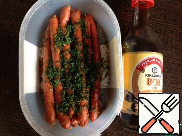 In a bowl, mix soy sauce and vegetable oil. I used soy sauce. Put the sausages in a bowl with sauce, sprinkle with herbs and cumin. And pepper to taste. Mix it.