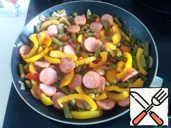Add the string beans, chopped sausage, finely chopped garlic and fry everything for 5 minutes. At the end, add the tomatoes cut into small cubes. Salt, pepper and fry for another minute.