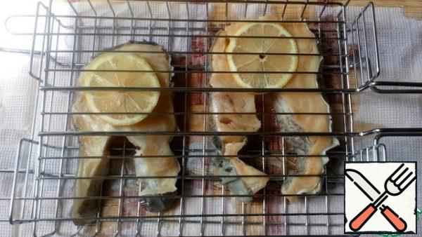 Cut the lemons into thin slices and place them on the grill. Put the fish on top and the lemons again. Cook the fish on both sides for about 10 minutes.
Fish under lemons turn out juicy, with a slight sourness, but not fried. If this option does not suit You, cook without lemons.