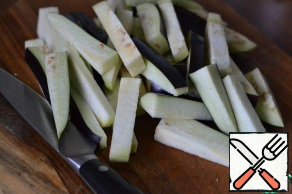 Grease the prepared baking dish with sunflower oil.
Cut the eggplant into medium-sized pieces or strips.