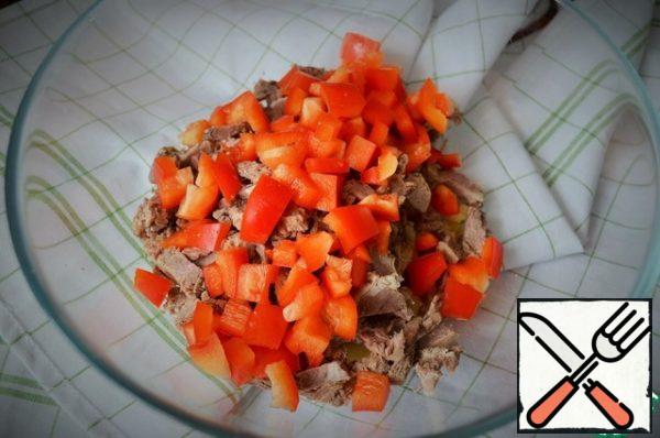 Wash the pepper and cut it into cubes.
Peel the onion, cut it into thin half-rings, and add the pepper to the meat and potatoes.