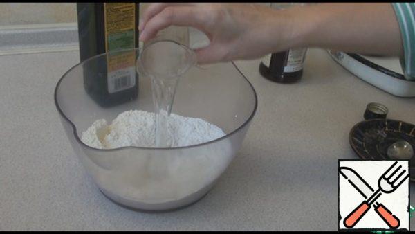 Add salt to the sifted flour and stir. Pour vinegar or lemon juice, water and knead the dough.