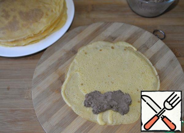 Let the pancakes cool slightly, but they should not be completely cold, otherwise they will lose their elasticity. Put about 2 tablespoons of pate on the edge of the pancake.