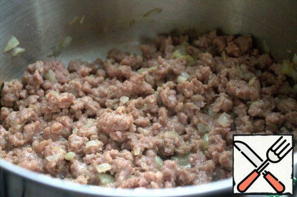 With a wooden spatula, we try to break the lumps of minced meat and fry them further with onions.