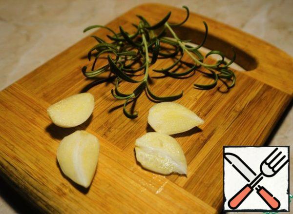 Peel the garlic and cut each clove in half. Preparing rosemary.