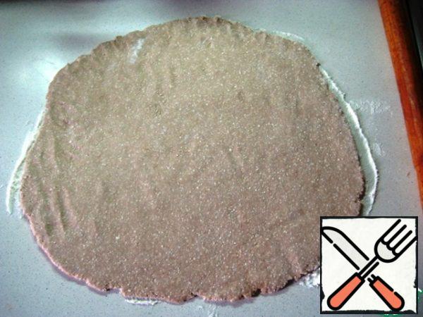 Divide the dough into 2 parts.

Dust the table with flour and roll out the dough into a circle about 0.5-0.7 mm thick.