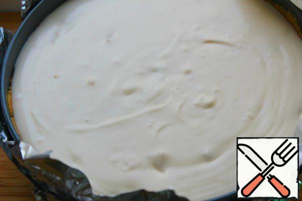 Wrap the form with foil - we will bake in a water bath.
Pour the cheesecake mixture onto the base.
Put the cheesecake mold in a large mold and pour boiling water to the height of a third of the cheesecake mold.
The oven is preheated to 160-165.
I baked for 70 minutes.
Leave in the oven with the door open for 15 minutes.