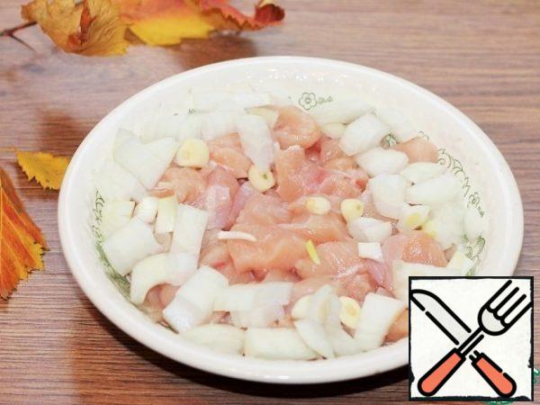 Prepare the filling. Chicken fillet cut into pieces, peeled onion and garlic slices.