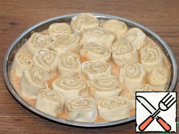 Cover the baking dish (f=26 cm) with baking paper or a silicone Mat. Pour 3-4 tablespoons of sauce in the middle and spread the portion rolls. Then fill the empty spaces carefully with the remaining sauce.
