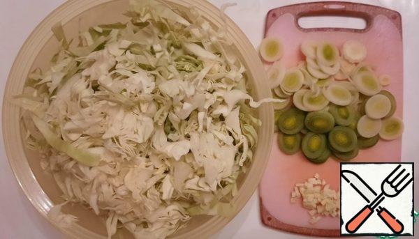 The soup is prepared very quickly, so before you start cooking, prepare everything for cooking. Cut the cabbage into thin strips. Cut the leeks into rings and finely chop the garlic.
