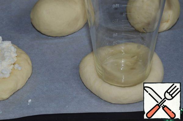 In the buns that come up, make depressions for the filling with the bottom of the glass.