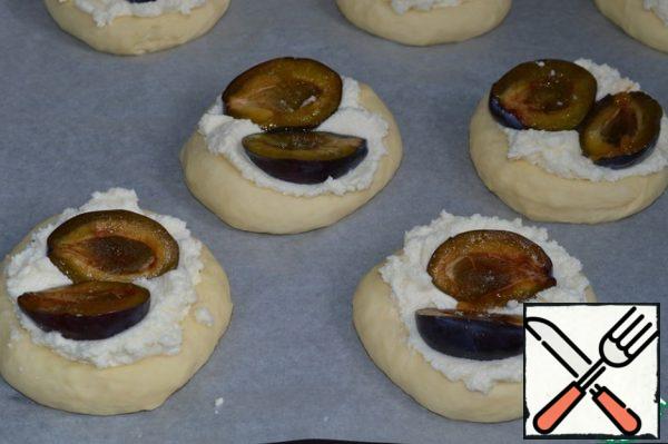 On each bun, put two halves of plums cut up, slightly drowning them in the curd filling.
Brush the edges of the buns with egg whipped with milk.
Sprinkle the buns with streusel.