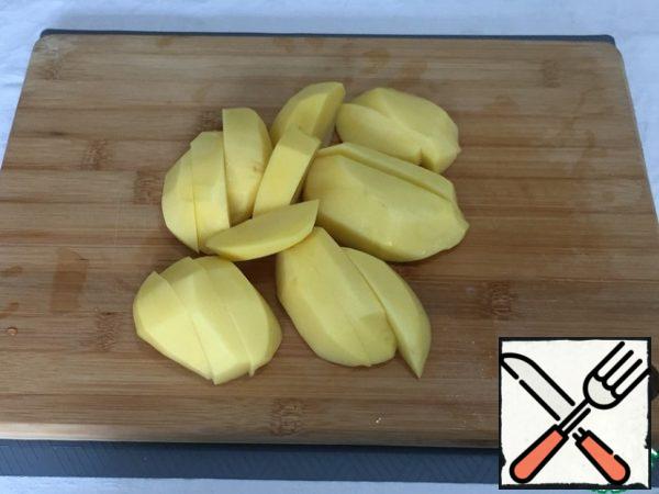 Meanwhile, peel the potatoes and cut them into slices.