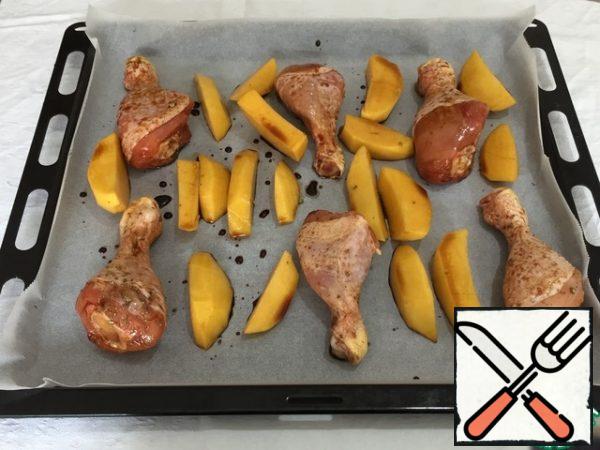 On a baking sheet covered with parchment paper, spread the chicken legs. In the remaining marinade, soak the potatoes. And also spread it on a baking sheet.