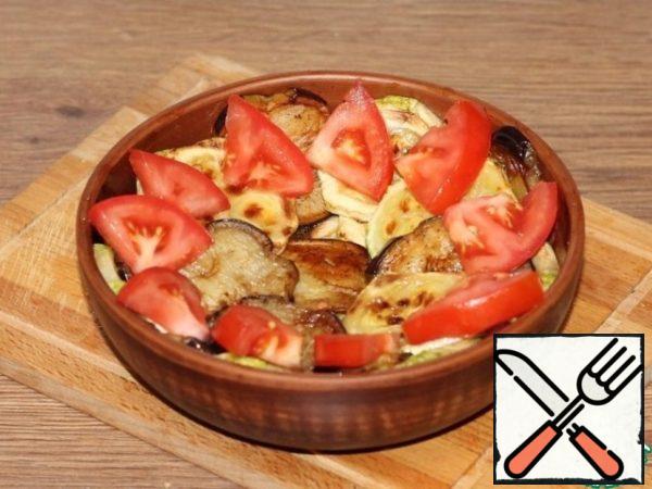 Arrange the eggplant and zucchini slices on a warm serving platter. In the middle, spread the dry potatoes and decorate the dish with tomato slices and herbs.
