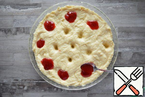 Put the dough in a 30 cm diameter mold and smooth it out with a spatula. Make small indentations on the entire surface of the pie with your finger or spoon and fill them with strawberry jam.Jam is better to take a thermostable, with the addition of pectin. It doesn't flow like that when baking.