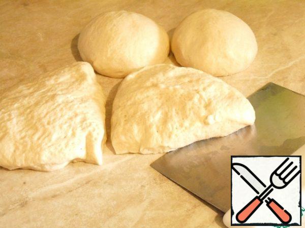 The dough has doubled in volume, the work surface and hands to lubricate with vegetable oil, put the dough out of the bowl, divide into a suitable amount, I divided into four parts. Each part is crushed and rolled into bulls. Lightly oil, cover with cling film, let the dough rest and rise.