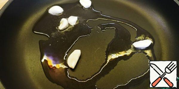 Pour the olive oil into the pan and add the garlic. And hot pepper, I didn't use it.
Turn on the water on the spaghetti, salt it.
