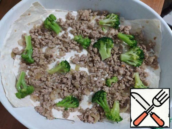 Put part of the minced meat and part of the broccoli on the pita bread. Pour 2/3 of a ladle of sauce. On top of the pita bread (cut it according to the size of the form, you can make up pieces)