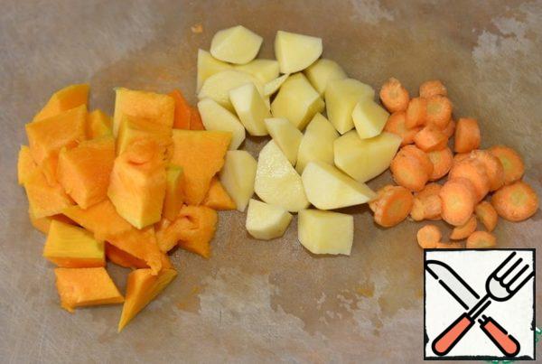 Vegetables are washed, cleaned, cut into cubes: pumpkin, potatoes, carrots.