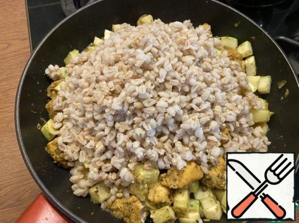 Then add sunflower oil. After adding the oil, pour the cooked pearl barley into the pan, mix well and close the lid. Simmer for 2 minutes.