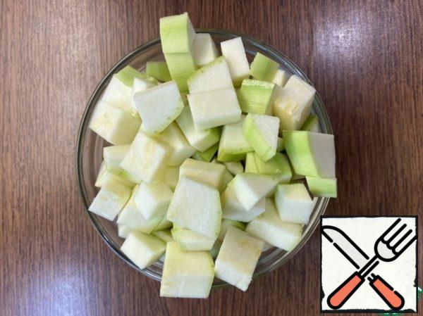 While the chicken fillet is cooking, cut the peeled zucchini into medium cubes.