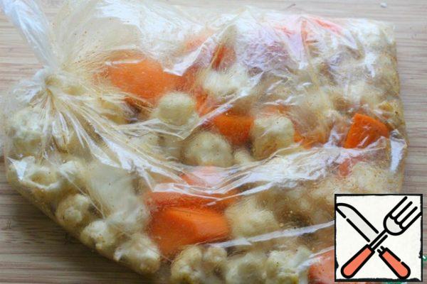 Pour vegetable oil into the bag, add cumin, paprika, salt, turmeric and pepper.
Tie the bag and mix the vegetables very well.