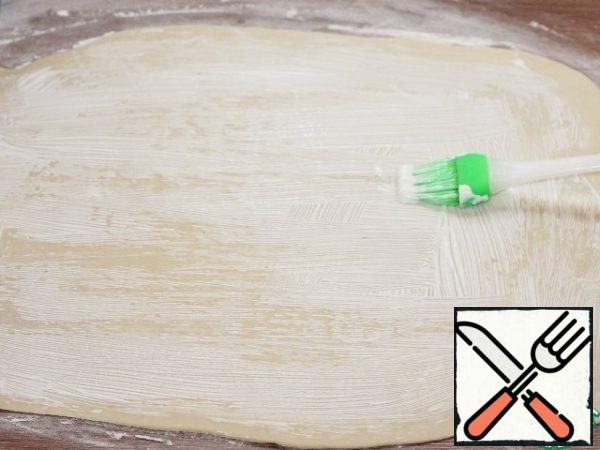 In 30 minutes, the dough became soft and very pliable. Dust the tabletop with flour (2 tablespoons) and thinly (2 ml) roll out the dough into a layer, ~ 40*36 cm. the thinner the dough layer, the tastier the rolls.
Lubricate the dough layer with sour cream (2 tablespoons) and let it soak for 3 to 5 minutes.