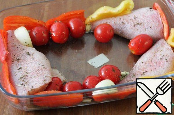 Put the prepared fish in a large baking dish and add the cherry and garlic.
I have added sweet pepper here, it's not necessary, I just love baked peppers and in the season I add it wherever I can.