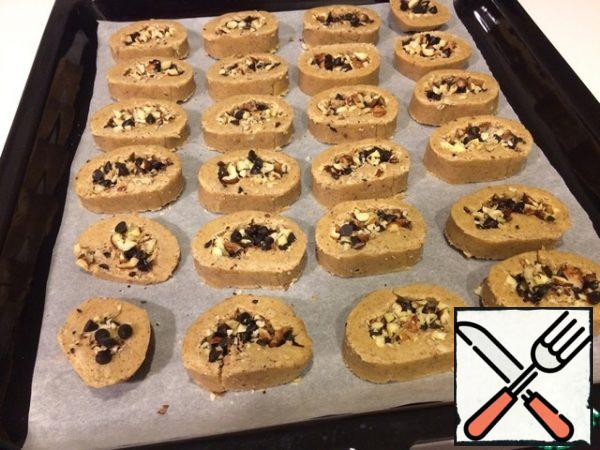 After an hour, we take it out of the freezer and cut it like a sausage in 1.5 cm pieces. Spread on a baking sheet lined with paper. If the filling will crumble, carefully distribute it back to the middle of the pieces already on the protvin. During baking, it will all catch on. I got 24 cookies.