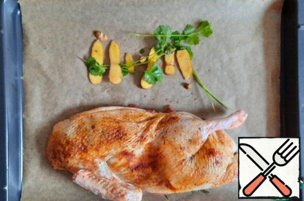 On a baking sheet covered with baking paper, the size of your oven is placed ginger (take from under the duck) and a couple of sprigs of coriander, put half of the duck skin on top of the ginger, and put the second part next to it.