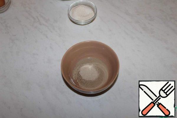 In warm water, add yeast and half a teaspoon of sugar from the total amount. Stir and leave in a warm place to rise.