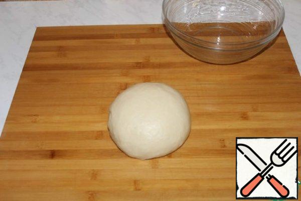 Knead the soft dough. Put the dough in a bowl and cover with cling film. We make holes in the film. And leave in a warm place to rise for 1 hour.